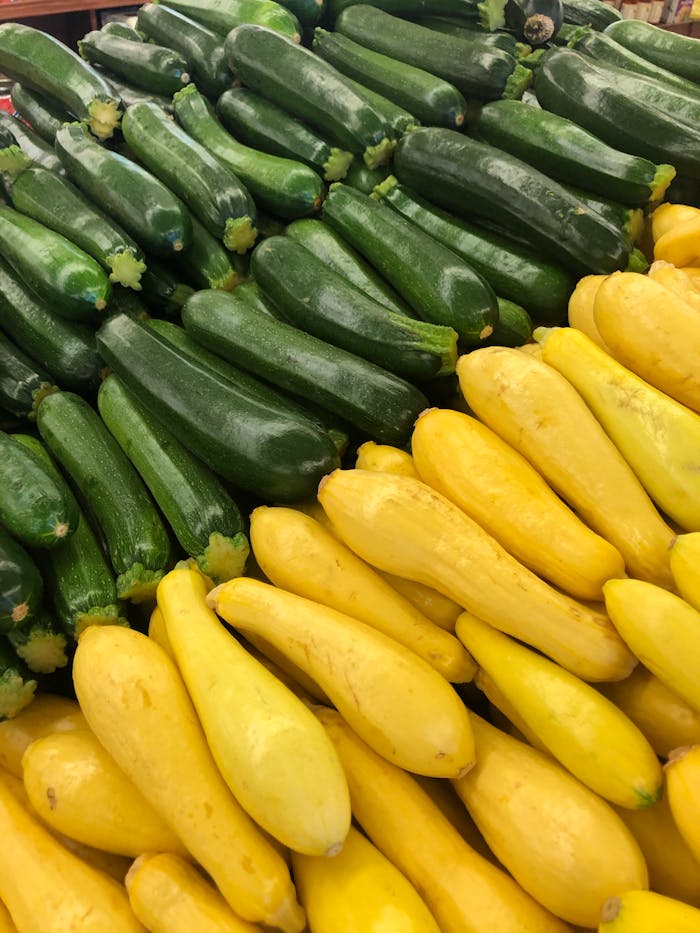 Vibrant display of fresh green zucchini and yellow squash at a farmer's market.